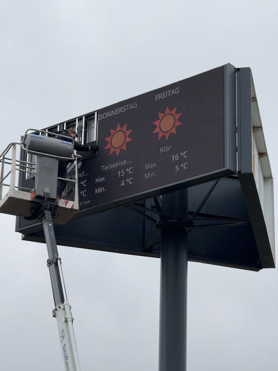 Mitarbeiter Jan repariert eine LED-Wand in luftiger Höhe