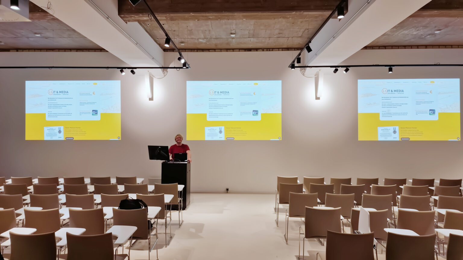 Seminarsaal mit drei Bildschirmprojektionen an der Wand